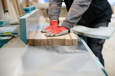 Ahşap endüstrisinde çalışan bir işçinin yakından görüntüsü. Mobilya yapımı için ahşap parçaları titizlikle kesip düzenliyor..