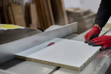 Ahşap endüstrisinde çalışan bir işçinin yakından görüntüsü. Mobilya yapımı için ahşap parçaları titizlikle kesip düzenliyor..