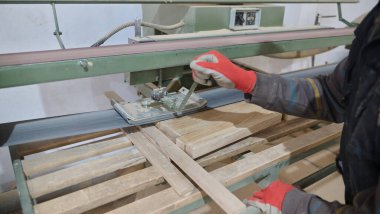 Ahşap endüstrisinde çalışan bir işçinin yakından görüntüsü. Mobilya yapımı için ahşap parçaları titizlikle kesip düzenliyor..