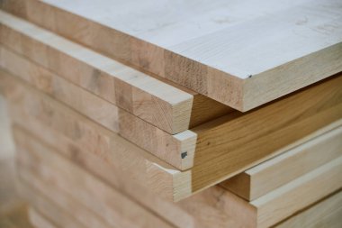 Çeşitli ahşap parçalar ve tahtalar CNC ahşap makinelerinde daha fazla işlem için hazırlanan bir depoda düzenli olarak depolanır..