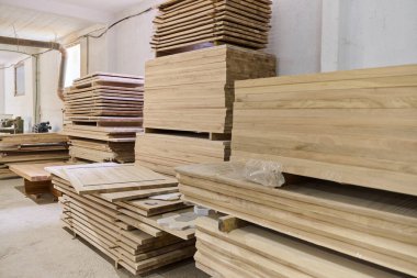 Çeşitli ahşap parçalar ve tahtalar CNC ahşap makinelerinde daha fazla işlem için hazırlanan bir depoda düzenli olarak depolanır..