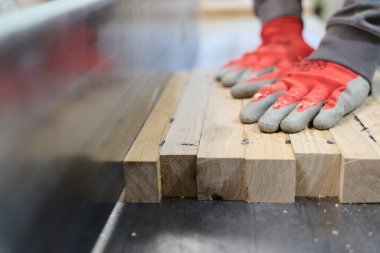 Ahşap endüstrisinde çalışan bir işçinin yakından görüntüsü. Mobilya yapımı için ahşap parçaları titizlikle kesip düzenliyor..