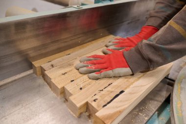 Ahşap endüstrisinde çalışan bir işçinin yakından görüntüsü. Mobilya yapımı için ahşap parçaları titizlikle kesip düzenliyor..