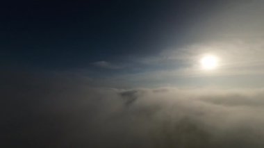 Dağlarda taze bir sabahta inanılmaz güzel bir bulutun içinden uçmak. Beyaz tüylü bulutlardan oluşan FPV insansız hava aracı açık mavi gökyüzünde usulca hareket ediyor