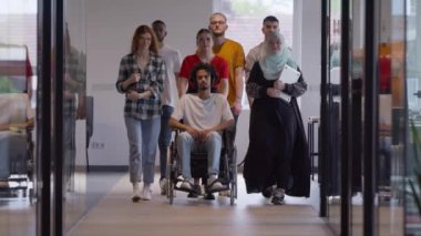 Genç iş adamlarından oluşan çeşitli bir grup, modern bir girişim olan cam kaplı bir ofiste, tekerlekli sandalyedeki bir kişi, bir Afrikalı Amerikalı genç adam ve bir tesettür ile bir araya geliyor.