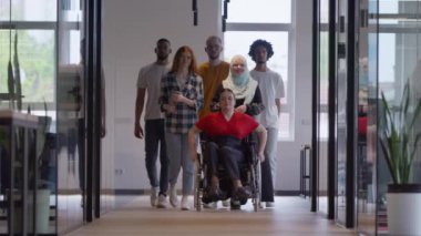 Genç iş adamlarından oluşan çeşitli bir grup, modern bir girişim olan cam kaplı bir ofiste, tekerlekli sandalyedeki bir kişi, bir Afrikalı Amerikalı genç adam ve bir tesettür ile bir araya geliyor.