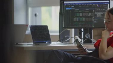 Modern bir iş kadını, mesai saatleri boyunca akıllı telefonunu kullanarak çağdaş bir ofiste mola verir.