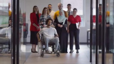 Genç iş adamlarından oluşan çeşitli bir grup, modern bir girişim olan cam kaplı bir ofiste, tekerlekli sandalyedeki bir kişi, bir Afrikalı Amerikalı genç adam ve bir tesettür ile bir araya geliyor.