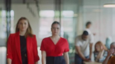 Kendine güvenen iş kadınlarından oluşan bir ekip modern bir başlangıç sahasının koridorlarında yürürken çapraz kollarla kendilerini işe adadıklarını gösteriyorlar.