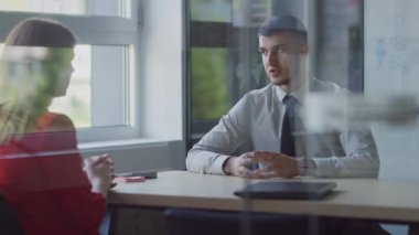 Bir yönetmen müşterisiyle olan sözleşmesini kesinleştirir, anlaşmayı sıkı bir tokalaşmayla imzalar, profesyonelliği ve modern ofis ortamındaki başarılı müşteri ilişkilerini örnek alır.