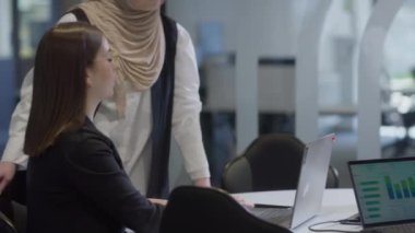 Bir tanesi tesettür takan çeşitli iş kadınlarından oluşan bir grup, bir dizüstü bilgisayara odaklanırken, tartışmalar ve problem çözme, göstermelik profesyonellik, takım çalışması ve etkili bir çalışma ile işbirliği yapıyor.