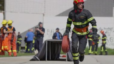 İtfaiyecilerden oluşan bir ekip, yangın söndürme görevine hazırlanmak için acilen su hortumlarını hazırlıyor ve yangın söndürme ve güvenliğe olan bağlılıklarını vurguluyor.