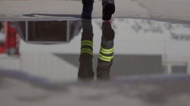 Yansıtıcı sahne, tehlikeli bir itfaiye görevine giden bir itfaiyeciyi yakalıyor. Yüzündeki cesaret ve hazırlığı simgeleyen bir yangın hortumunu tutarken görüntüsü su yüzeyinde yansıtılıyor.