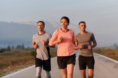 Bir grup arkadaş, sporcu ve koşucu sabahın erken saatlerinde güneşin doğuşuyla enerji dolu ve doğanın sakin güzelliğiyle çevrelenmiş bir şekilde puslu şafakta koşarken kucaklaşıyorlar.. 