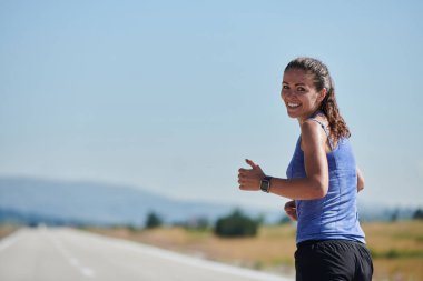 An athletic woman finds freedom and joy in a healthy lifestyle, running through a beautiful road trail at sunrise.  clipart