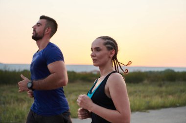 A vibrant couple dashes running the outdoors, embodying the essence of athleticism and romance, their confident strides reflecting a shared commitment to fitness and preparation for future marathon clipart