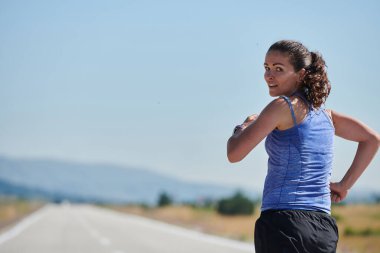 An athletic woman finds freedom and joy in a healthy lifestyle, running through a beautiful road trail at sunrise.  clipart