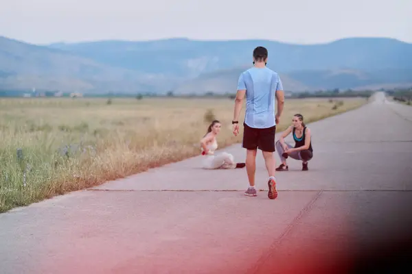 stock image In a dynamic display of unity and preparation, a diverse group of athletes warm up together, readying themselves for a challenging running endeavor.