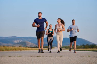 Bir grup arkadaş, güneşli bir günde dışarıda koşuşturarak sağlıklı bir yaşam tarzını sürdürüyor. Spor ve doğanın enerji verici etkilerinden keyif alıyorlar.. 