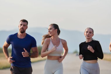 Bir grup arkadaş, güneşli bir günde dışarıda koşuşturarak sağlıklı bir yaşam tarzını sürdürüyor. Spor ve doğanın enerji verici etkilerinden keyif alıyorlar.. 