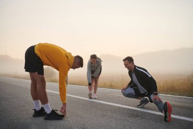 Hareketli ve çeşitli bir grup sporcu esneme ve ısınma egzersizleriyle meşgul, birliklerini ve hareketli bir sabah koşusuna hazır olduklarını gösteriyorlar..