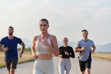 Bir grup arkadaş, güneşli bir günde dışarıda koşuşturarak sağlıklı bir yaşam tarzını sürdürüyor. Spor ve doğanın enerji verici etkilerinden keyif alıyorlar.. 