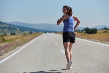 An athletic woman finds freedom and joy in a healthy lifestyle, running through a beautiful road trail at sunrise.  clipart