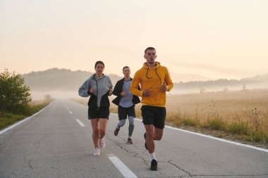 Bir grup arkadaş, sporcu ve koşucu sabahın erken saatlerinde güneşin doğuşuyla enerji dolu ve doğanın sakin güzelliğiyle çevrelenmiş bir şekilde puslu şafakta koşarken kucaklaşıyorlar.. 