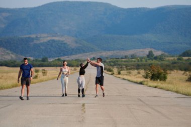 Bir grup arkadaş, güneşli bir günde dışarıda koşuşturarak sağlıklı bir yaşam tarzını sürdürüyor. Spor ve doğanın enerji verici etkilerinden keyif alıyorlar.. 