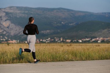 An athletic woman finds freedom and joy in a healthy lifestyle, running through a beautiful road trail at sunrise.  clipart