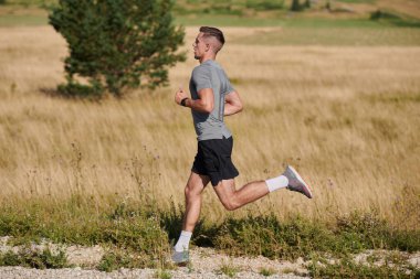 Atletik bir adam koşarken kararlılığını sergiler, sağlıklı bir yaşam tarzına ve yaklaşan maraton yarışmasına hazırlanmaya bağlıdır.