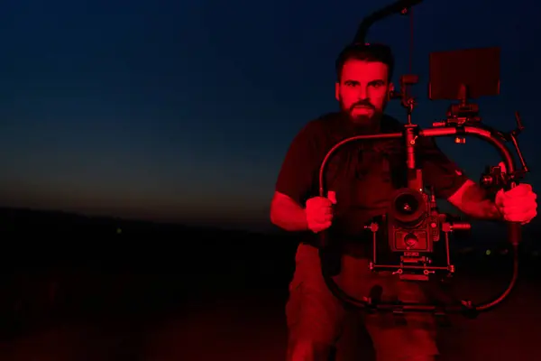 stock image A skilled videographer captures the intensity of athletes running, illuminated by vibrant red lights, encapsulating the energy and determination of their nighttime training session.