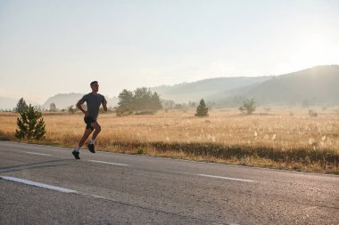 Atletik bir adam koşarken kararlılığını sergiler, sağlıklı bir yaşam tarzına ve yaklaşan maraton yarışmasına hazırlanmaya bağlıdır.