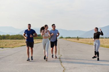 Bir grup arkadaş, güneşli bir günde dışarıda koşuşturarak sağlıklı bir yaşam tarzını sürdürüyor. Spor ve doğanın enerji verici etkilerinden keyif alıyorlar.. 