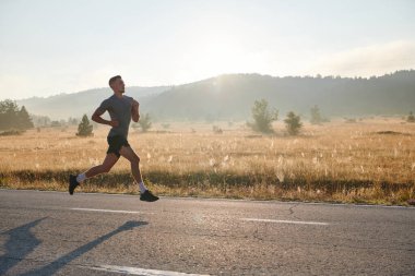 Atletik bir adam koşarken kararlılığını sergiler, sağlıklı bir yaşam tarzına ve yaklaşan maraton yarışmasına hazırlanmaya bağlıdır.