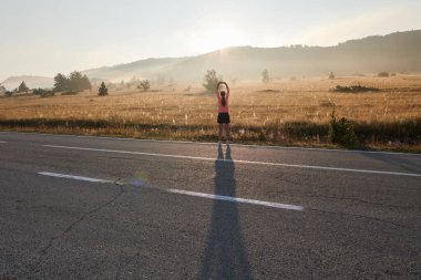  Kararlı bir atletik kadın koşudan sonra esneme hareketleri yapar, spor yolculuğuna kendini adamaya ve vücudunun esnekliğini ve esnekliğini arttırmaya çalışır.