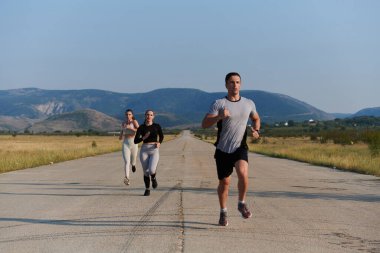 Bir grup arkadaş, güneşli bir günde dışarıda koşuşturarak sağlıklı bir yaşam tarzını sürdürüyor. Spor ve doğanın enerji verici etkilerinden keyif alıyorlar.. 