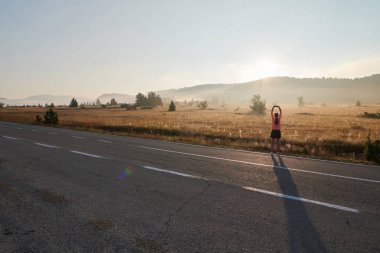  Kararlı bir atletik kadın koşudan sonra esneme hareketleri yapar, spor yolculuğuna kendini adamaya ve vücudunun esnekliğini ve esnekliğini arttırmaya çalışır.