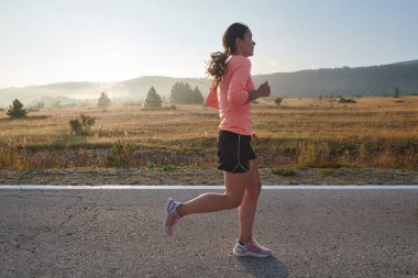 Kararlı ve motive olmuş bir sporcu gün doğumuna güvenle koşuyor, sabah koşusunda kararlılığını ve gücünü özetliyor.. 