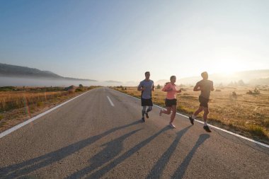 Bir grup arkadaş, sporcu ve koşucu sabahın erken saatlerinde güneşin doğuşuyla enerji dolu ve doğanın sakin güzelliğiyle çevrelenmiş bir şekilde puslu şafakta koşarken kucaklaşıyorlar.. 