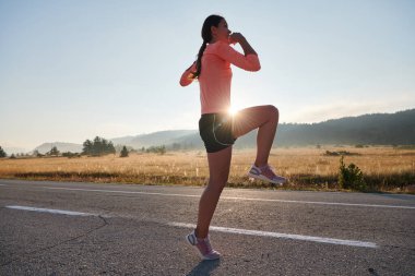  Kararlı bir atletik kadın koşudan sonra esneme hareketleri yapar, spor yolculuğuna kendini adamaya ve vücudunun esnekliğini ve esnekliğini arttırmaya çalışır.