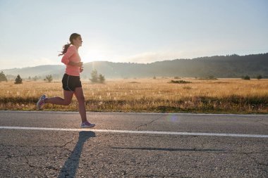 Kararlı ve motive olmuş bir sporcu gün doğumuna güvenle koşuyor, sabah koşusunda kararlılığını ve gücünü özetliyor.. 