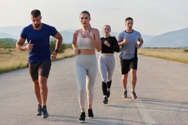 Bir grup arkadaş, güneşli bir günde dışarıda koşuşturarak sağlıklı bir yaşam tarzını sürdürüyor. Spor ve doğanın enerji verici etkilerinden keyif alıyorlar.. 