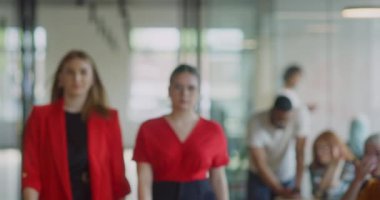 Kendine güvenen iş kadınlarından oluşan bir ekip modern bir başlangıç sahasının koridorlarında yürürken çapraz kollarla kendilerini işe adadıklarını gösteriyorlar.