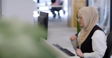 Modern bir ofiste, başörtüsü takan Müslüman bir girişimci güvenli ve gayretli bir şekilde bilgisayarında oturur, kararlılığı, yaratıcılığı ve iş dünyasının güçlendirilmesini somutlaştırır.. 