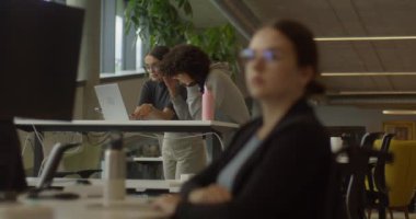 Tekerlekli sandalyedeki bir iş kadını, modern bir ofiste dizüstü bilgisayarla çalışırken görülüyor, dahil olma, erişilebilirlik ve profesyonelliğe değer veren bir iş yeri örneği.