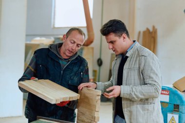 Bir yapım müdürü çalışanına çeşitli dekoratif ve konut ahşap eşyalar, ahşap endüstrisi üretim süreci ve tekniklerini sergileme talimatı verir..