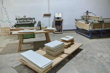 CNC kesme makinelerinin ve çeşitli ahşap işleme ekipmanlarının sergilendiği bir ahşap işleme tesisinin iç görünümü.