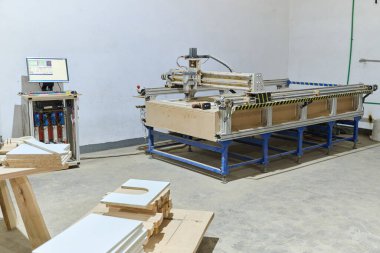CNC kesme makinelerinin ve çeşitli ahşap işleme ekipmanlarının sergilendiği bir ahşap işleme tesisinin iç görünümü.