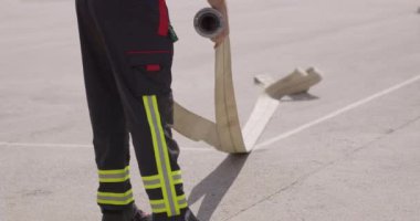 Profesyonel bir itfaiyeci, tehlikeli bir operasyondan sonra yangın hortumlarını titizlikle temizleyip depoluyor ve bu da ameliyat sonrası bakım ve güvenlik protokollerinin önemini gösteriyor.